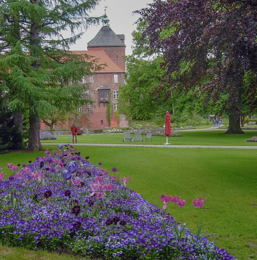 Wiese mit Bäumen vor einem Ziegelsteingebäude