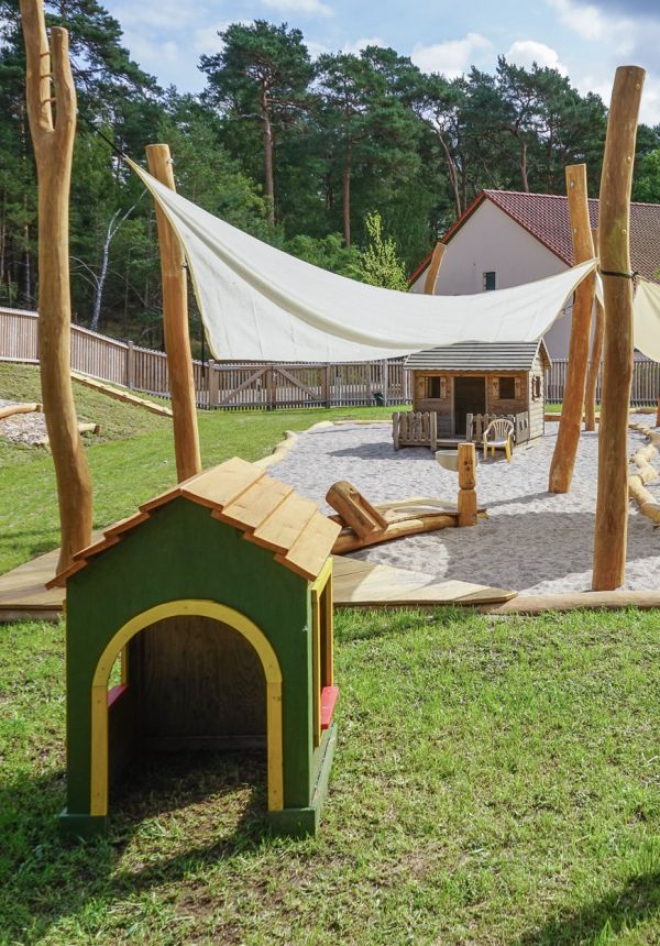 Sicht auf den Spielplatz, im Vordergrund ein kleines, grünes Spielhaus