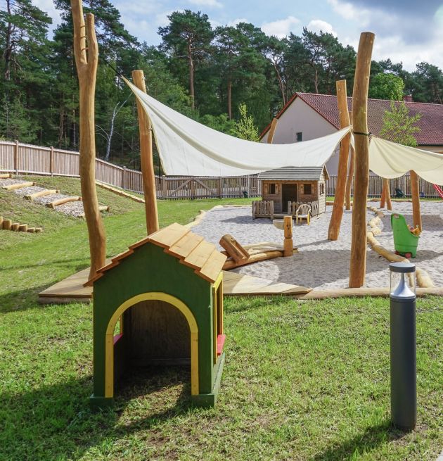 Sicht auf den Spielplatz, im Vordergrund ein kleines, grünes Spielhaus
